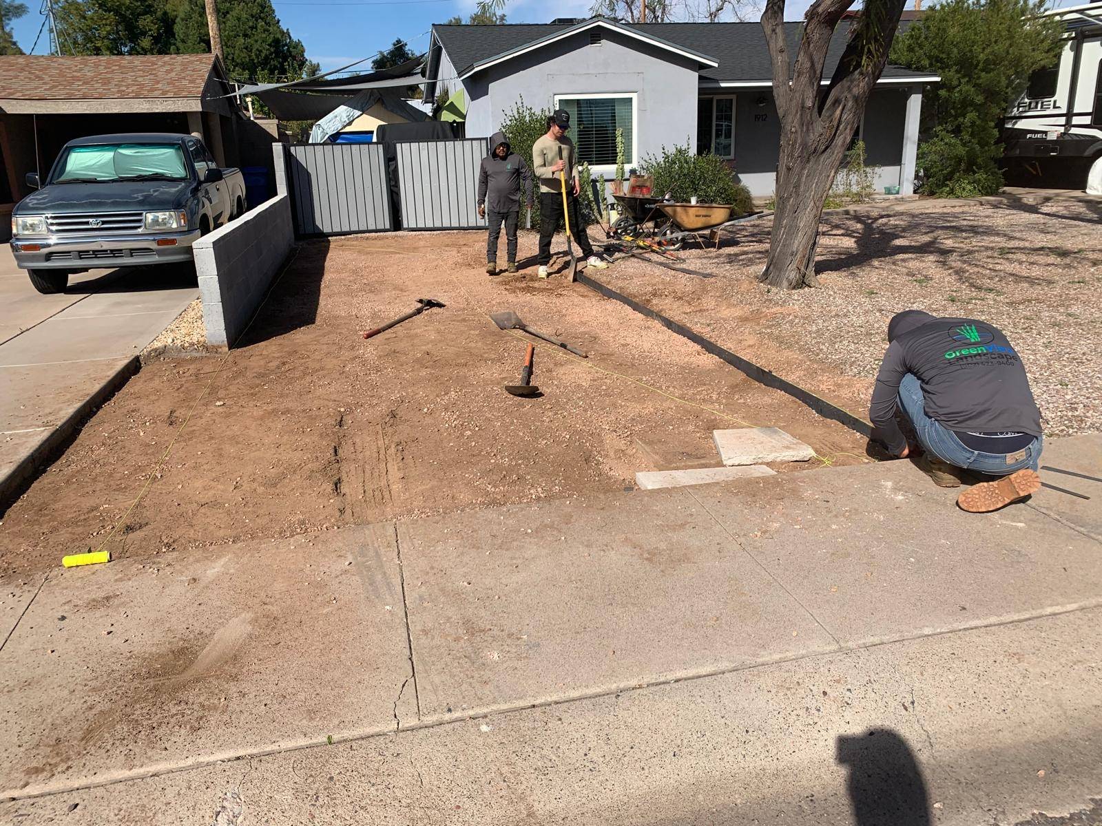 Crew leveling a dirt area in front of a house