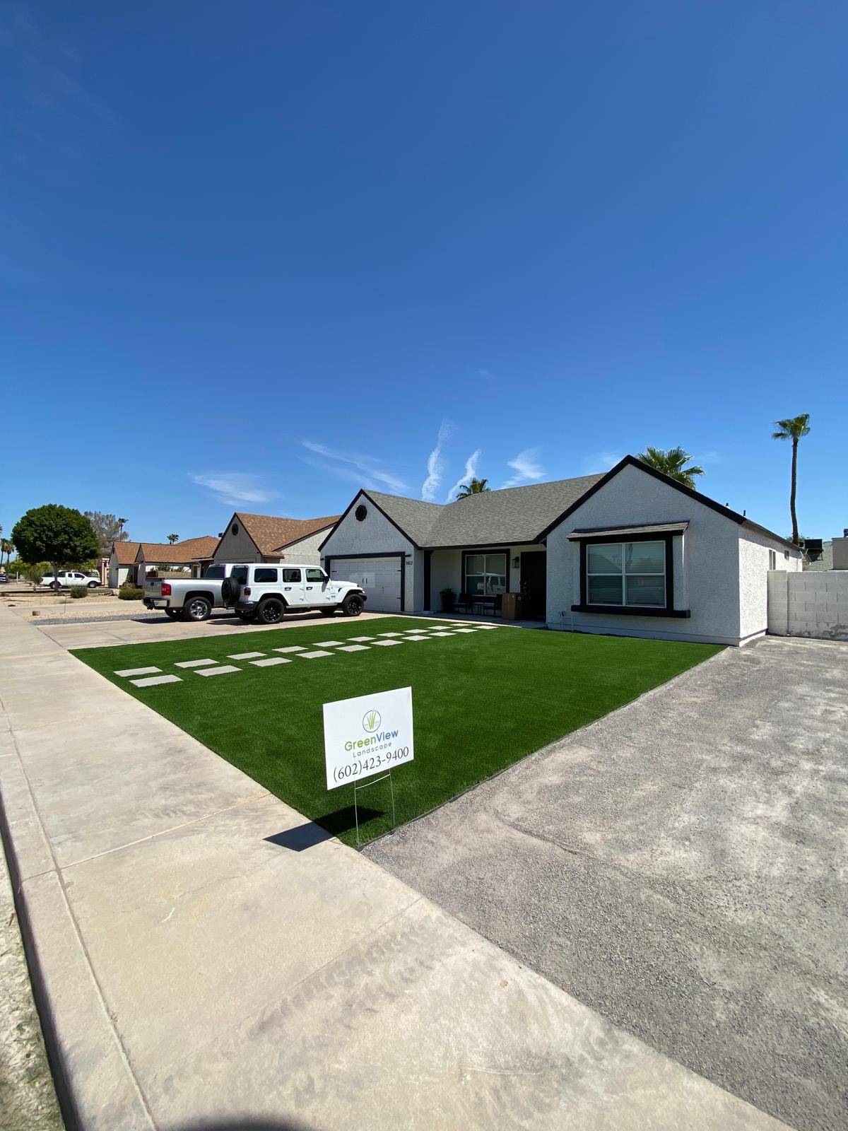 Front yard with new artificial turf and stepping stones, with a GreenView Landscape sign