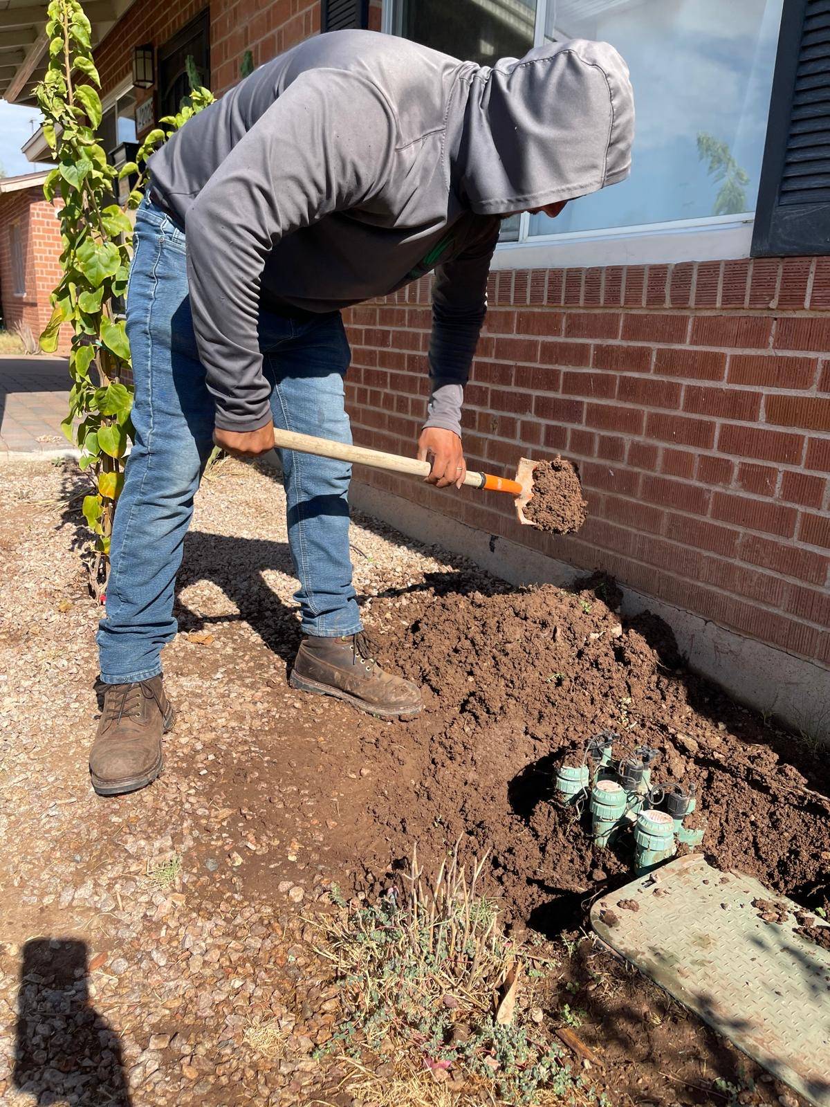 Crew member digging around a row of sprinkler valves